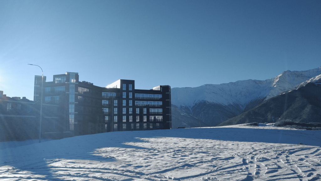 Hôtel moderne en montagne en Tchétchénie avec sommets enneigés du Caucase en arrière-plan