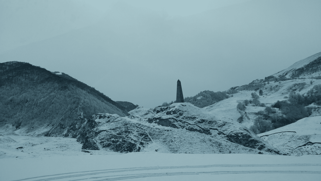 Chechen medieval stone tower in snowy mountains near Lake Kezenoy-Am