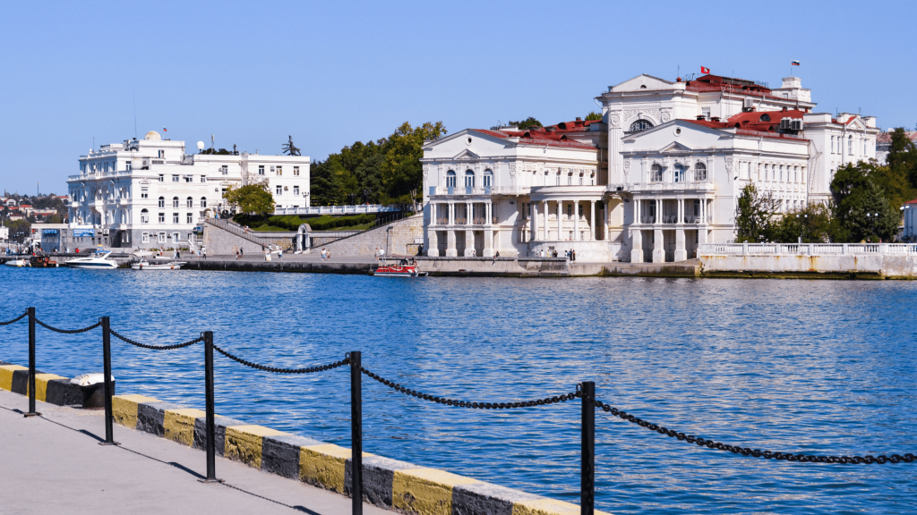 Historic white waterfront buildings along Sevastopol harbor with blue sea in foreground