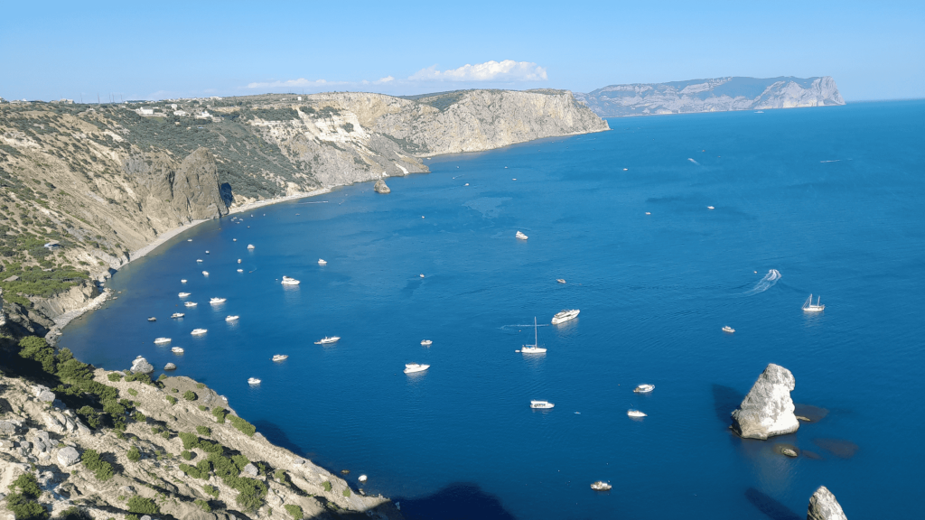 Cliffs of Cape Fiolent with boats in turquoise water near Yashmovy Beach in Crimea