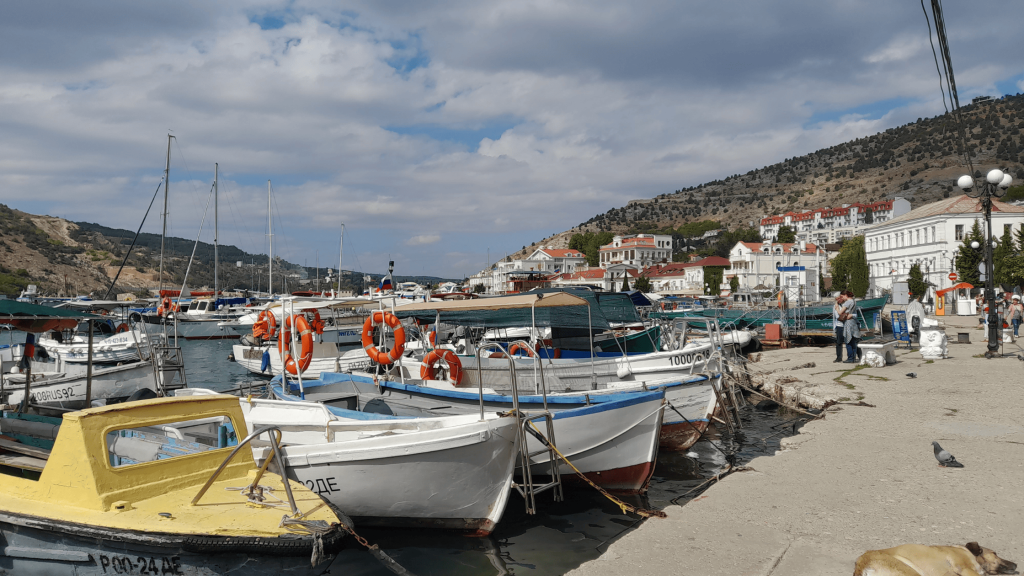 Petits bateaux amarrés dans le port de Balaklava en Crimée avec les bâtiments blancs en arrière-plan