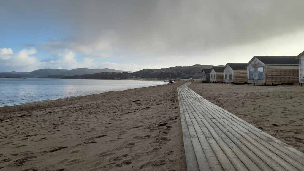Plage de sable avec cabanes en bois et passerelle à Teriberka dans la région de Mourmansk