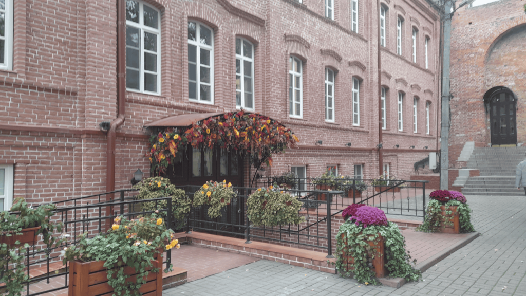 Entrance of a red brick Pestrikov hotel in Smolensk decorated with colorful flowers