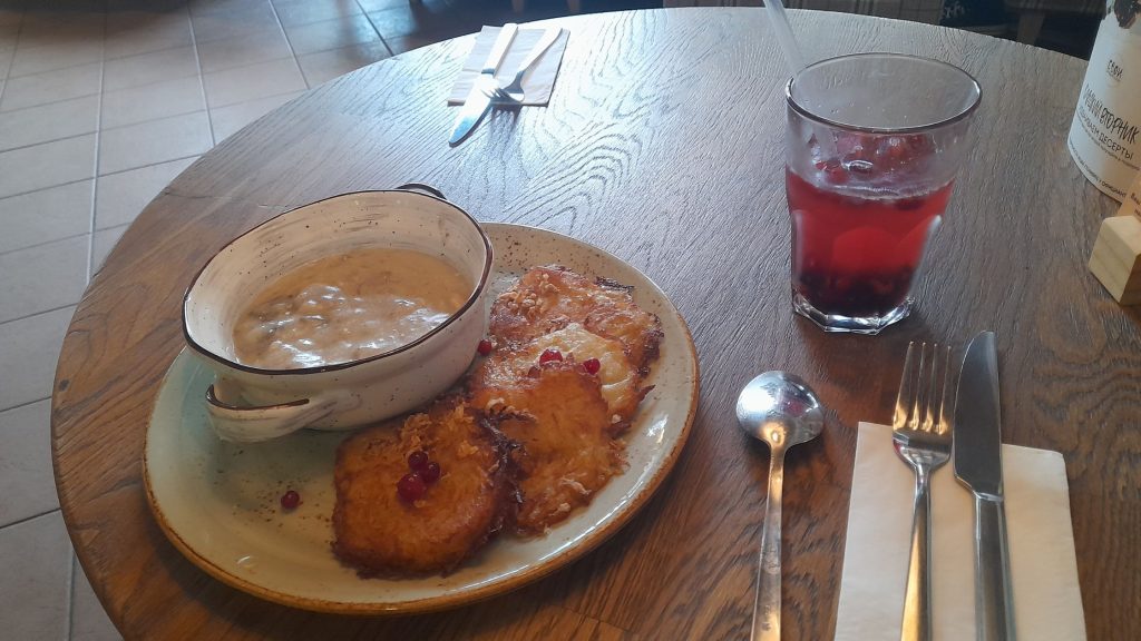 Plate of draniki with machanka sauce and berry drink in Minsk