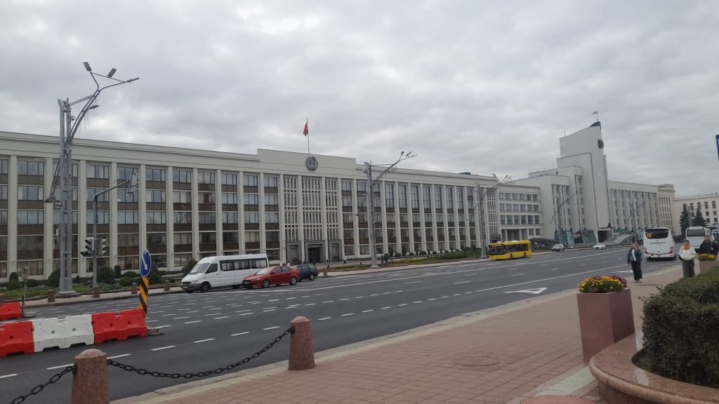 Minsk City Council building facing a wide avenue in Minsk, Belarus, with traffic and pedestrians.