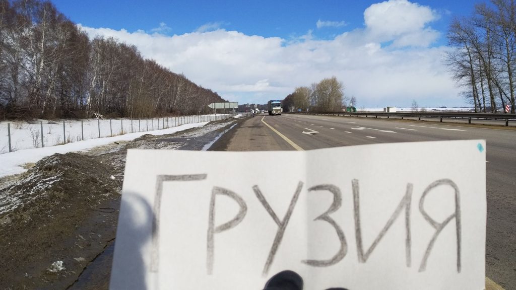 Panneau d’autostop pour la Géorgie écrit en russe au bord d’une route enneigée en Russie