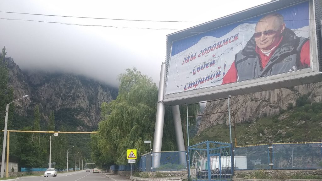 Large billboard featuring Vladimir Putin in a mountainous Russian-speaking region during a road trip in the former Soviet world