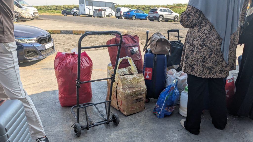 Voyageurs azerbaïdjanais avec leurs bagages attendant un transport après la frontière turque