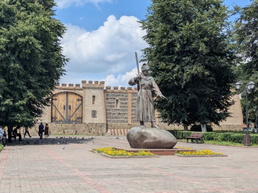 Statue de Dzaug Bugulov devant les murailles reconstituées de la forteresse à Vladikavkaz